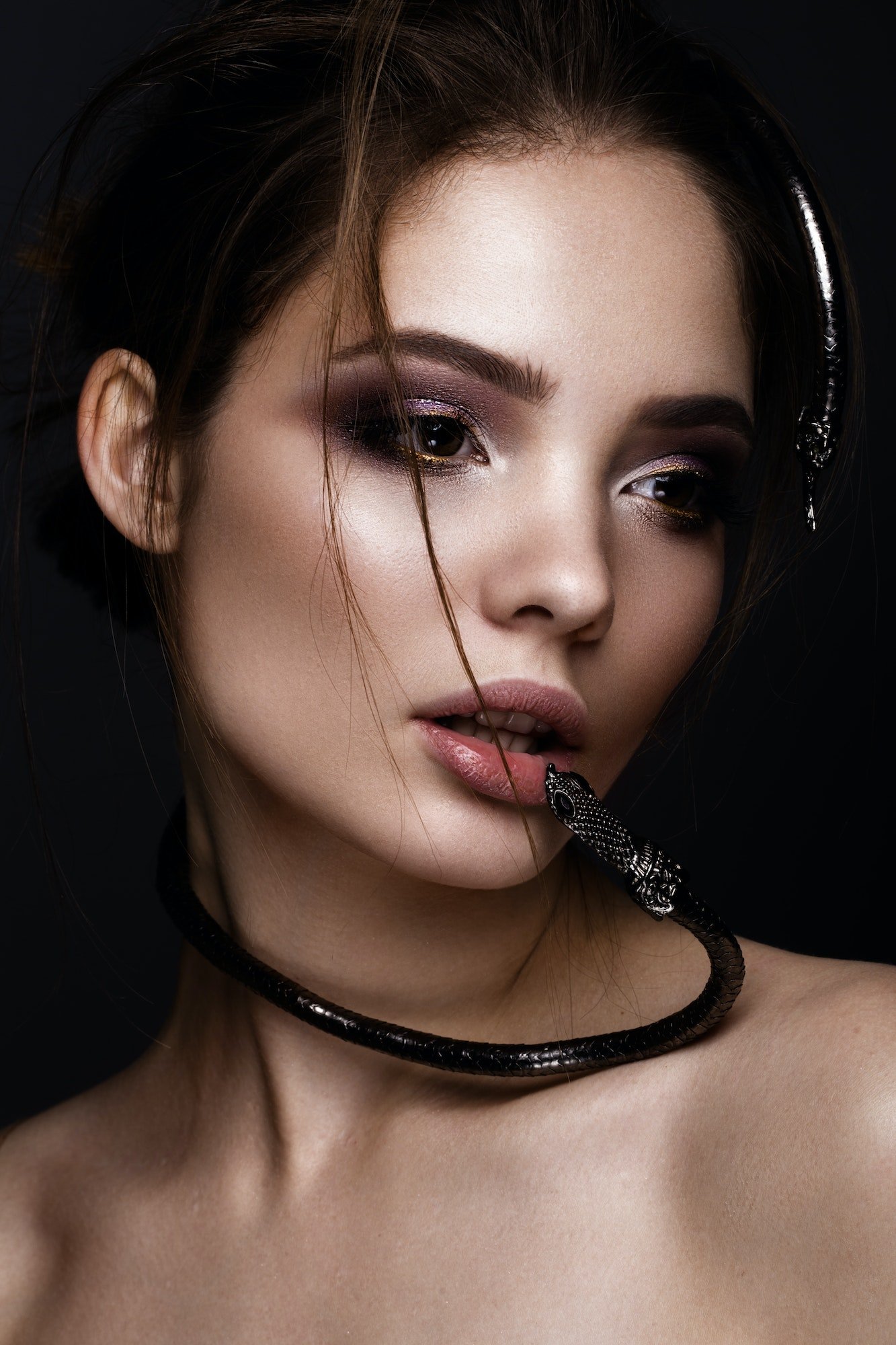 Beautiful girl with bright makeup and fashionable hair, decoration in form of snake. beauty face.